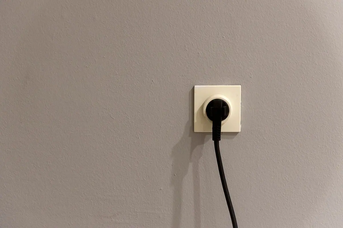 Enchufe de pared con un aparato conectado, en una pared pintada de gris