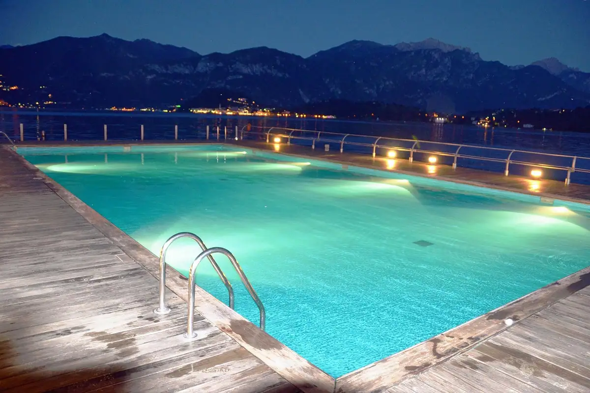 Piscina comunitaria iluminada de noche por sus focos subacuáticos