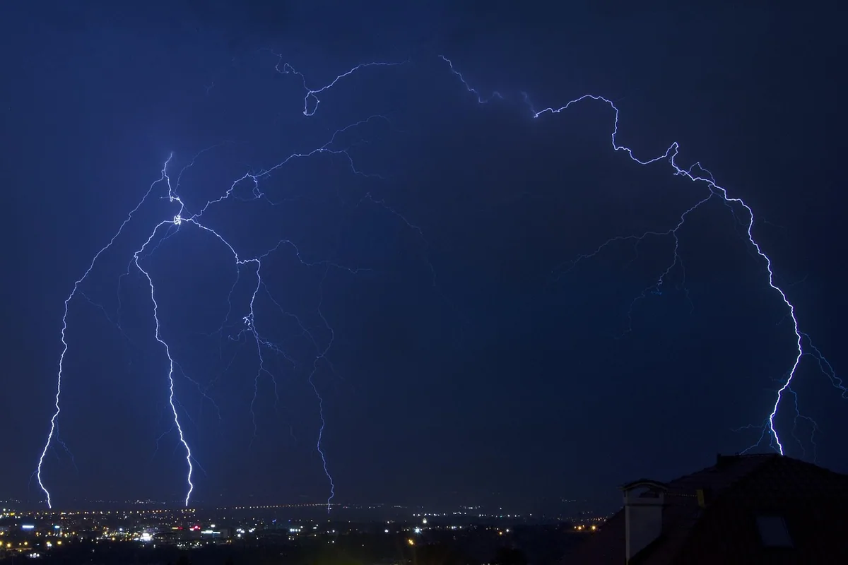 Rayos de una tormenta nocturna sobre las luces de una ciudad, una de las causas de las sobretensiones en la red eléctrica