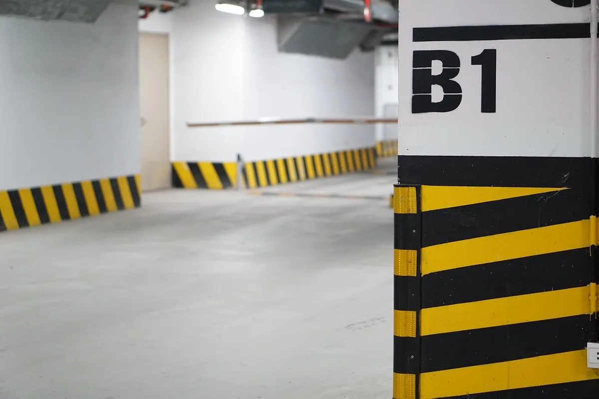 Garaje comunitario subterráneo con columnas señalizadas en amarillo y negro, lugar habitual para instalar un punto de recarga
