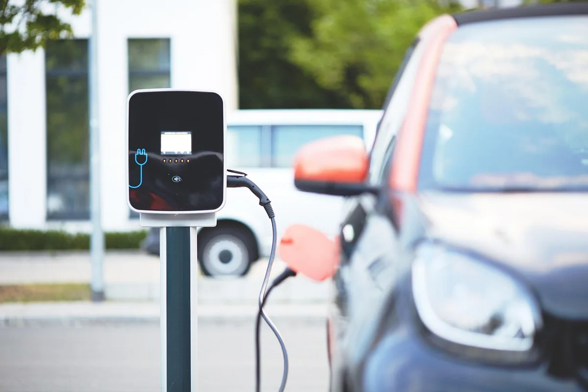 Punto de recarga para coche eléctrico en una plaza de aparcamiento, con el cable de carga conectado a un coche
