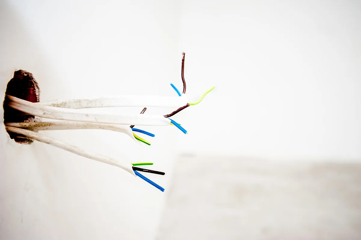 Cables saliendo de una caja empotrada, con el conductor de protección verde y amarillo que va a la toma de tierra de la instalación eléctrica