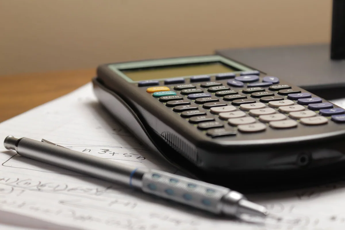 Calculadora y portaminas sobre hojas con cuentas a mano, como al calcular el precio de un electricista antes de empezar